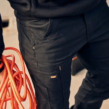 Load image into Gallery viewer, Person holding orange coiled cable wearing dark pants and a black jacket with white text.
